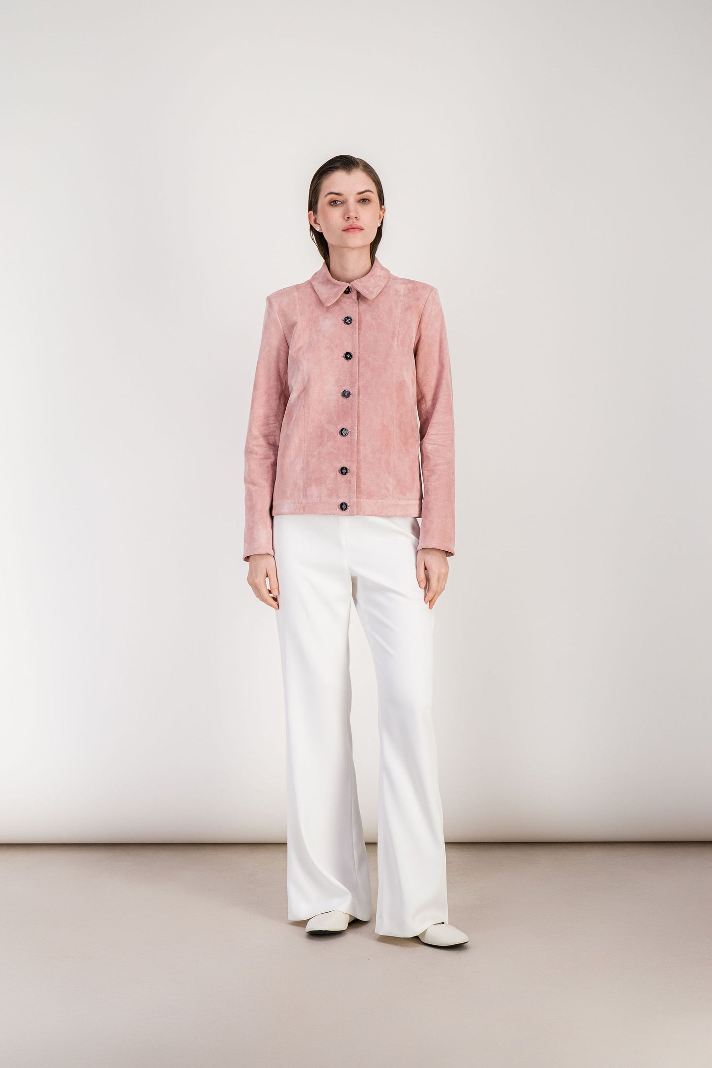 Veste élégante rose clair avec découpes verticales et silhouette ajustée.