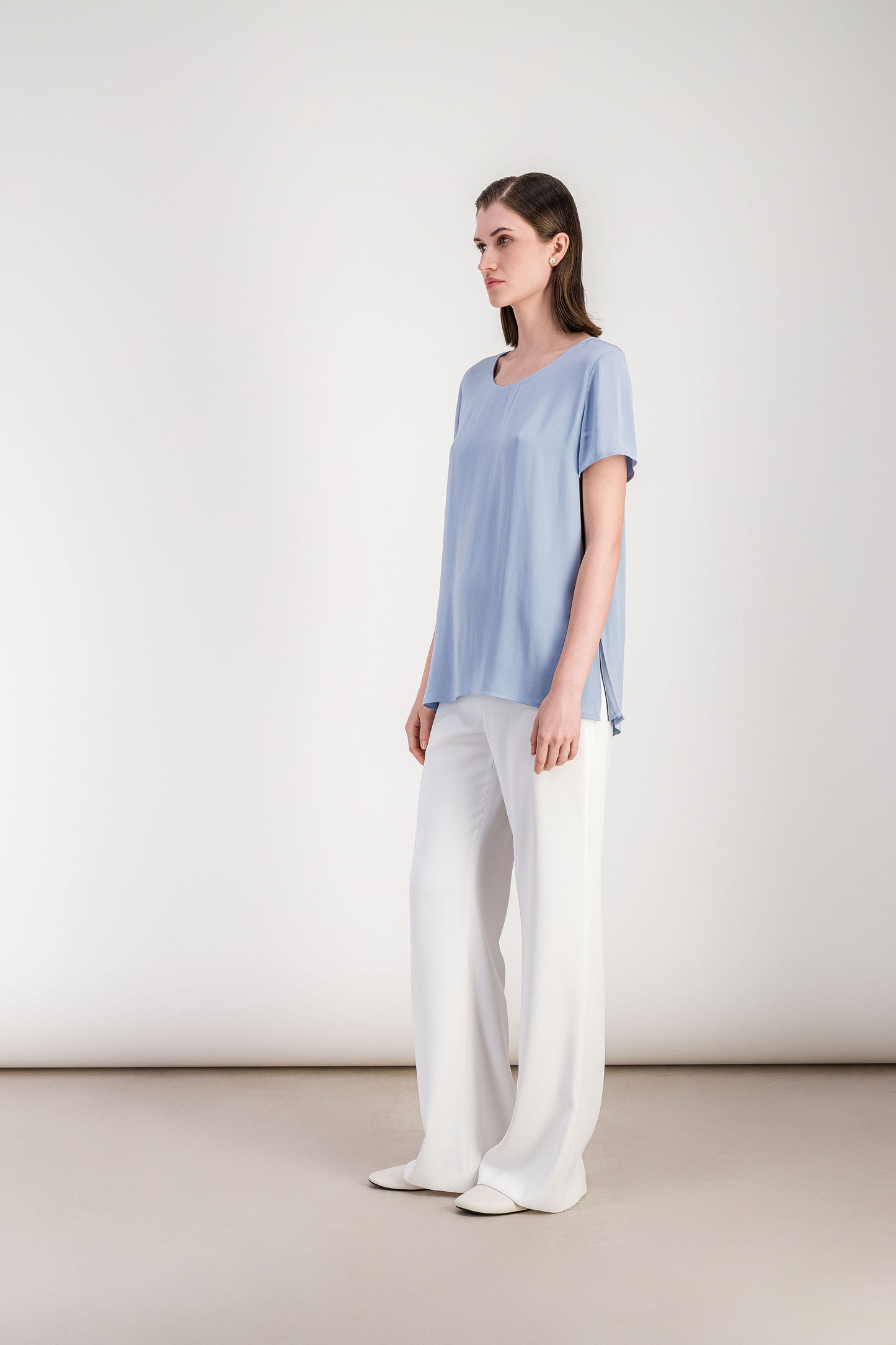 Blouse minimaliste bleu denim avec manches courtes et ligne épurée.