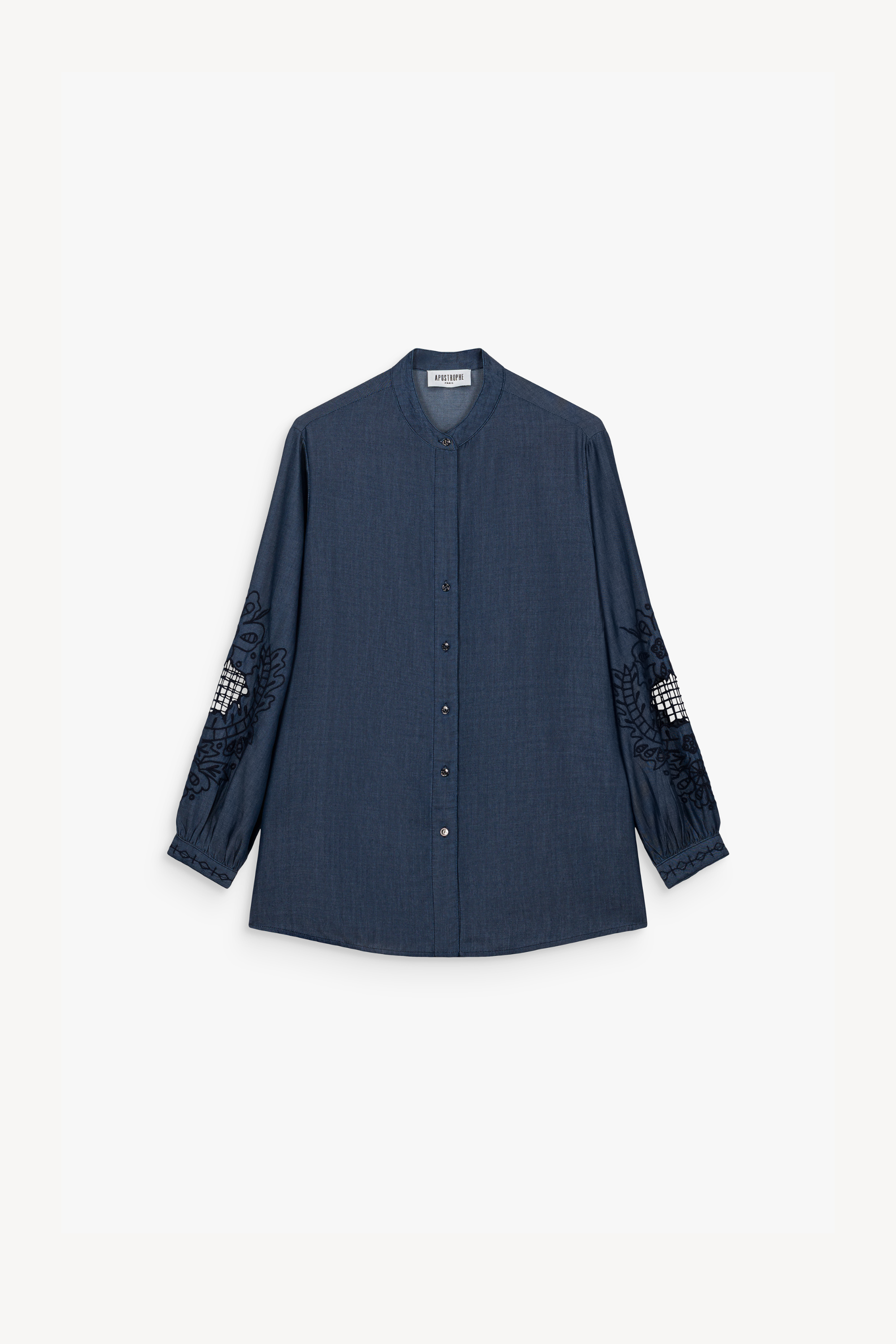 Blouse en chambray bleu délavé, souple et résistante, avec col mao contemporain. Broderies délicates aux manches et patte de boutonnage cachée.