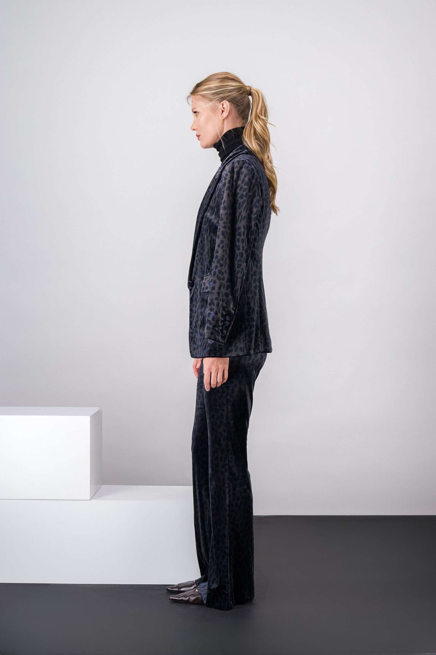 Pantalon élégant en velours noir, motif léopard, mouvement fluide.