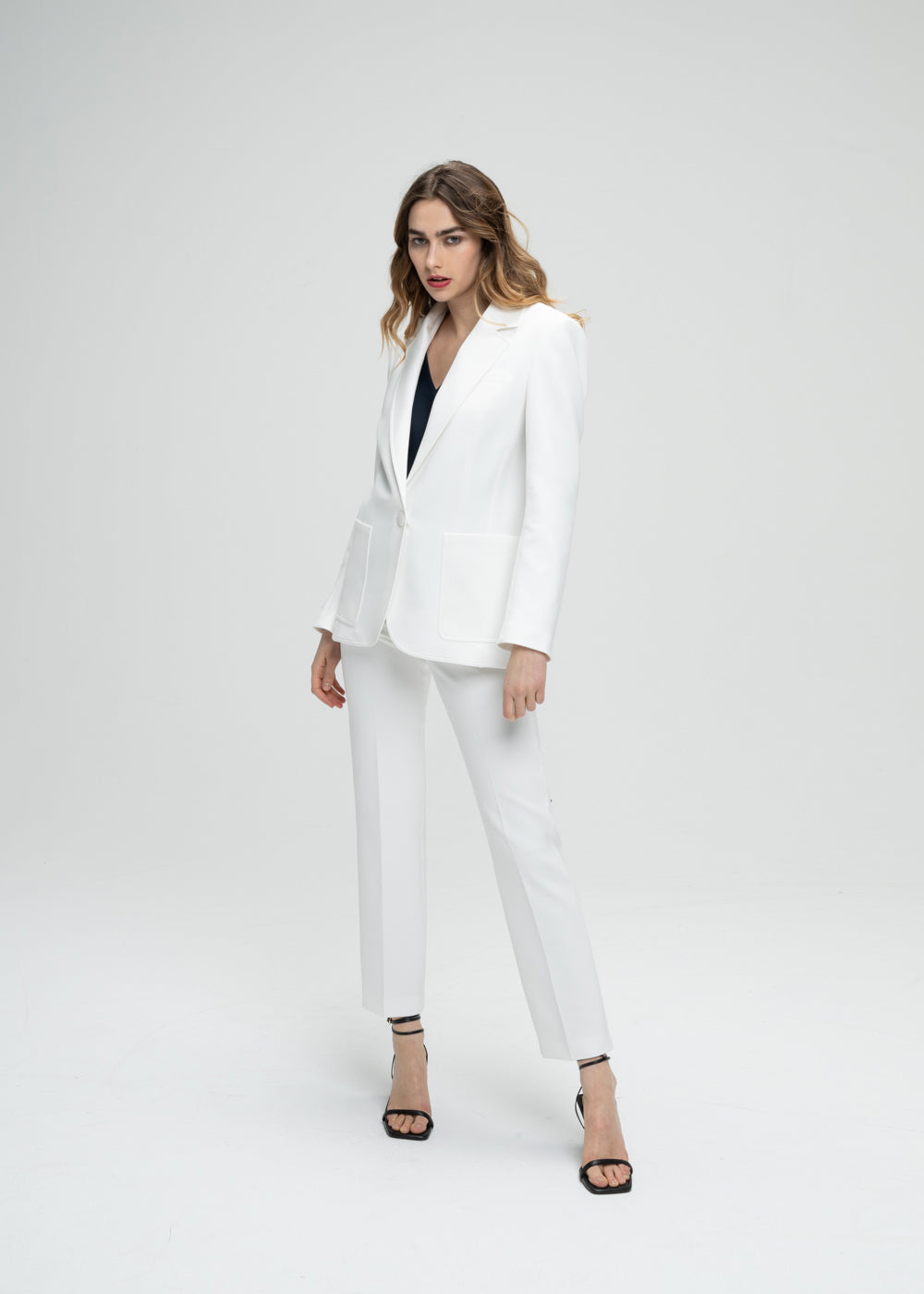 Veste tailleur cintrée blanc avec poches plaquées, col tailleur et détail monogramme manche