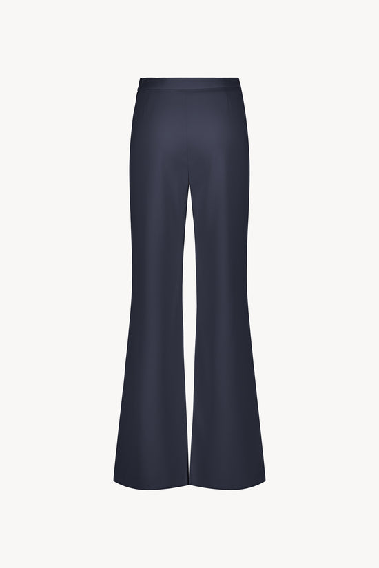 Pantalon marine taille haute à pont. Coupe évasée fluide. Boutons bombés ton sur ton à la ceinture.