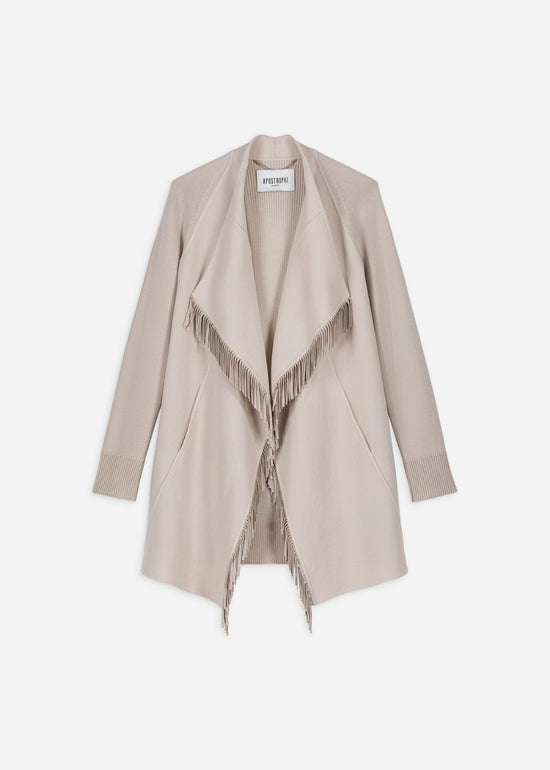 Ce manteau court bi-matière béton combine laine douce et daim, avec un col drapé fluide et des franges décoratives.
