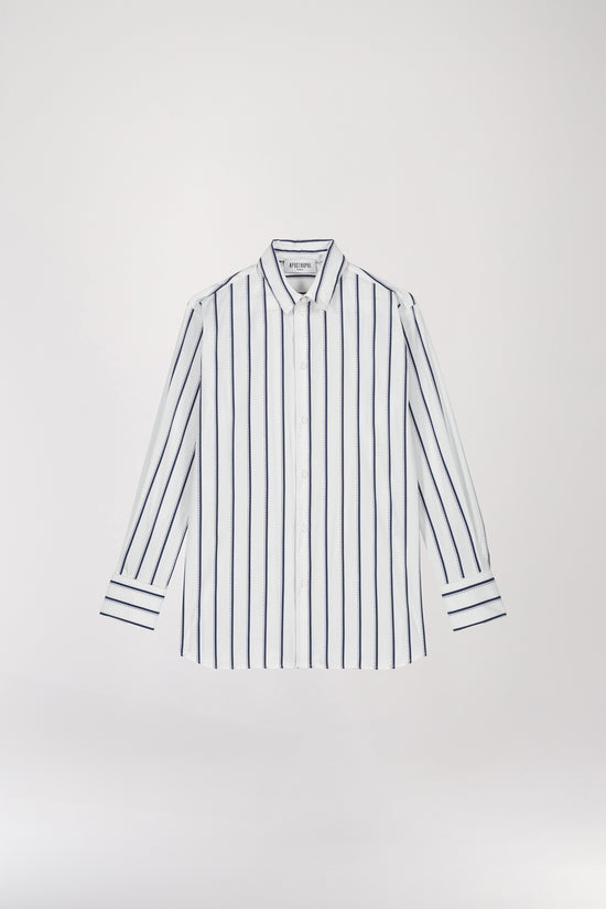 Chemise rayée marine en coton à coupe droite, dotée d'un col structuré et de boutons nacrés apparents à l'avant et aux poignets pour un ajustement parfait. Les rayures horizontales sur les emmanchures et le dos ajoutent une touche de sophistication à cette pièce élégante.