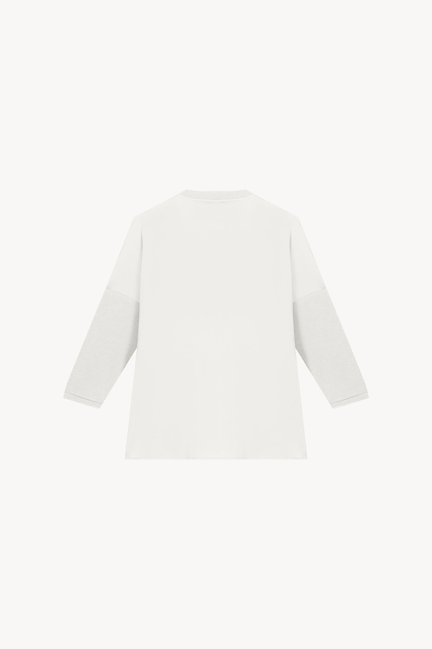 Tunique bi-matière jersey blanche, élégante et au look distingué, offrant un effet texturé qui sublime la silhouette. Avec des manches en jersey côtelé, un col côtelé et des fentes latérales, elle allie confort et sophistication.