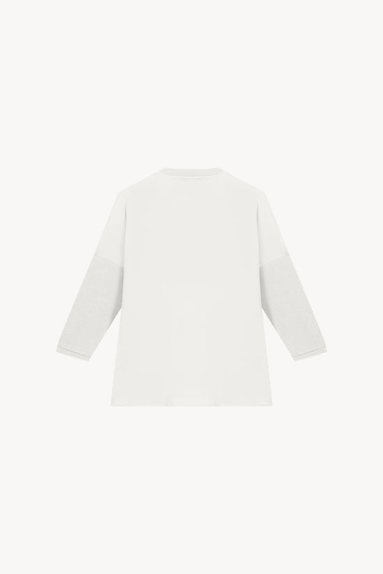 Tunique bi-matière jersey blanche, élégante et au look distingué, offrant un effet texturé qui sublime la silhouette. Avec des manches en jersey côtelé, un col côtelé et des fentes latérales, elle allie confort et sophistication.