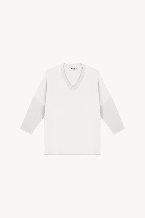 Tunique bi-matière jersey blanche, élégante et au look distingué, offrant un effet texturé qui sublime la silhouette. Avec des manches en jersey côtelé, un col côtelé et des fentes latérales, elle allie confort et sophistication.