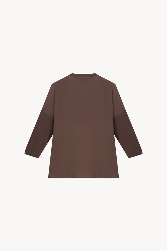 Tunique bi-matière jersey taupe, élégante et au look distingué, avec un effet texturé qui sublime la silhouette. Dotée de manches en jersey côtelé, d’un col côtelé et de fentes latérales, elle allie confort et sophistication.