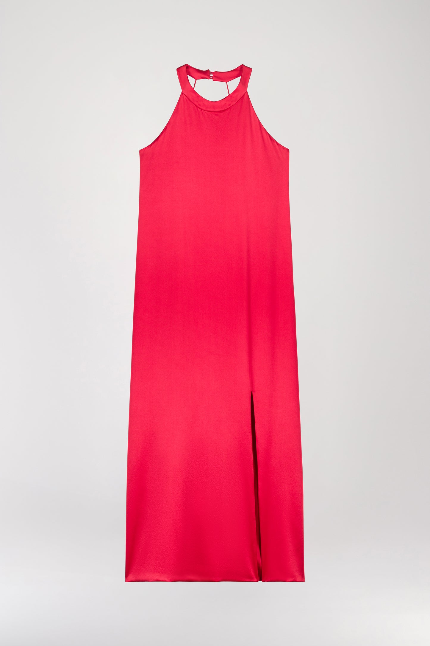 Robe longue dos nu en soie corail, avec une coupe fluide et chic. Elle présente un col montant, une encolure en U, et une fente avant pour un mouvement élégant. Un zip invisible assure un ajustement parfait, tandis que le décolleté minimaliste dans le dos ajoute une touche raffinée.