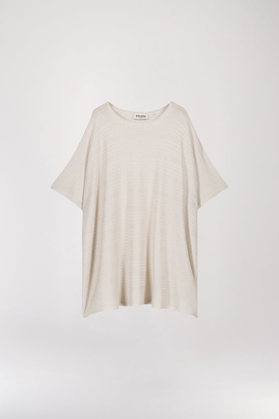 Pull poncho blanc cassé à coupe ample, orné de détails ajourés et de paillettes dorées pour une touche minimaliste. Son col arrondi ajoute une note de féminité à ce modèle élégant.