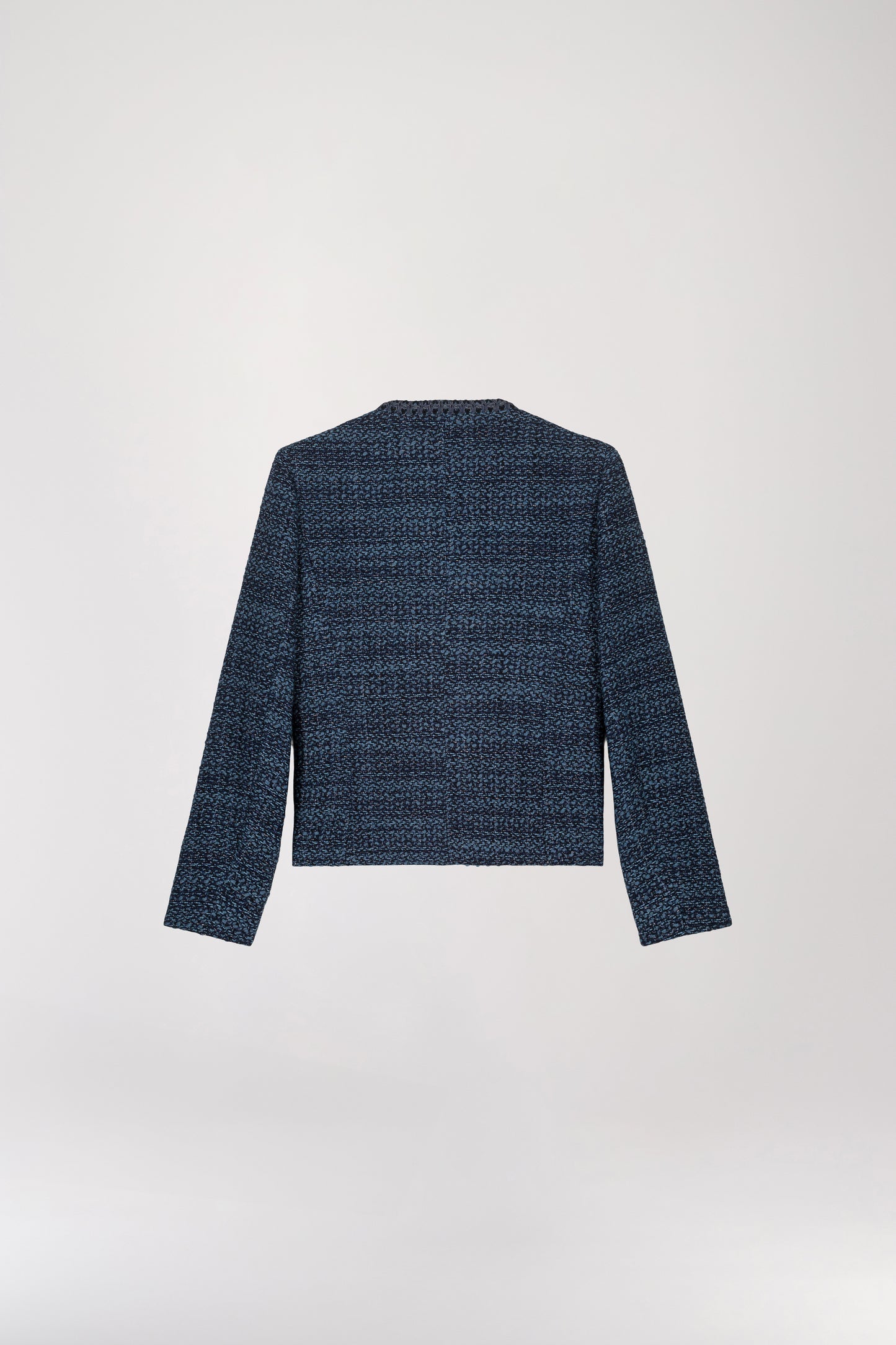 Veste courte en tweed bleu denim présentant une coupe structurée, un col arrondi, des bordures tressées, un boutonnage apparent et des poches italiennes.