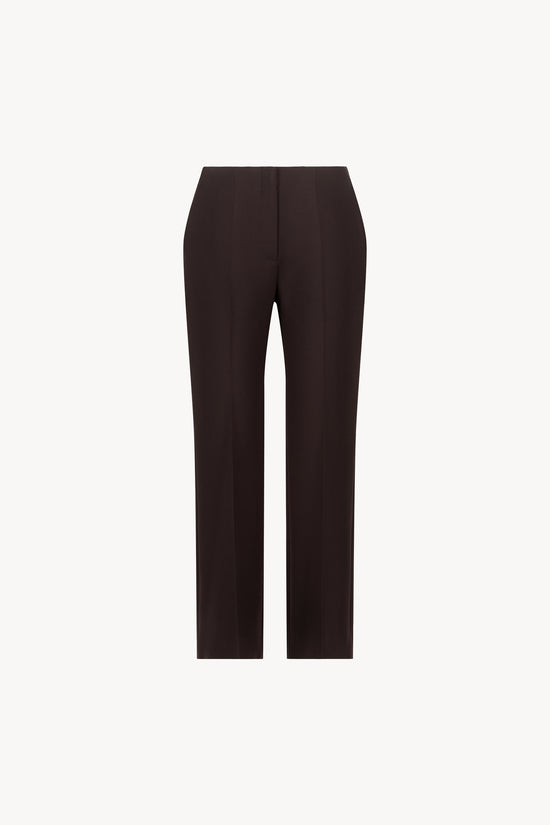 Pantalon ébène orné d'un pli de presse et d'une patte boutonnée cachée.