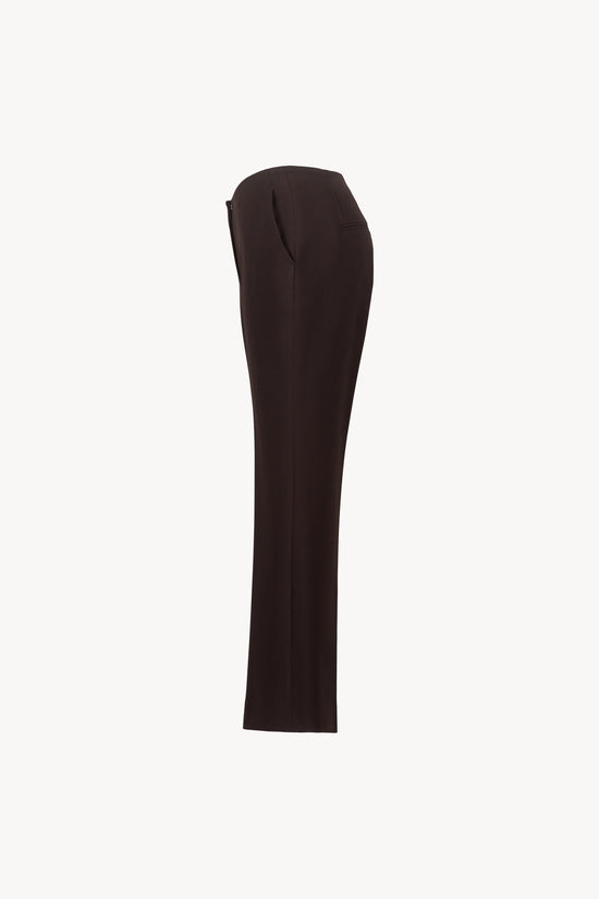 Pantalon ébène orné d'un pli de presse et d'une patte boutonnée cachée.