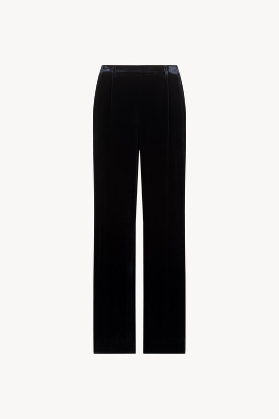 Ce pantalon droit en velours de soie bleu marine avec des plis raffinés et une coupe parfaite.