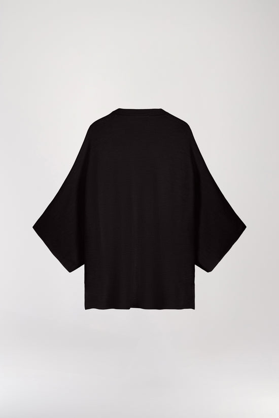 Pull poncho en laine noire, avec une coupe ample oversize, des manches 3/4 et un col rond côtelé.