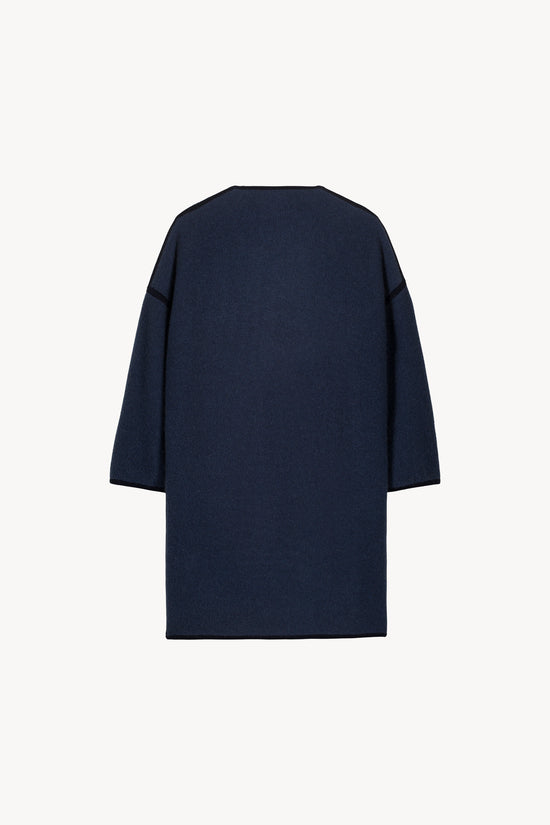 Manteau bicolore bleu denim doté de finitions bicolores, poches plaquées et de col ample.