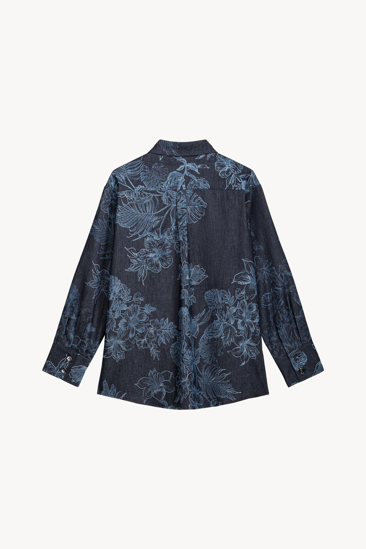 Cette chemise en denim révèle un jeu de contrastes subtils entre le motif floral et les finitions soignées.