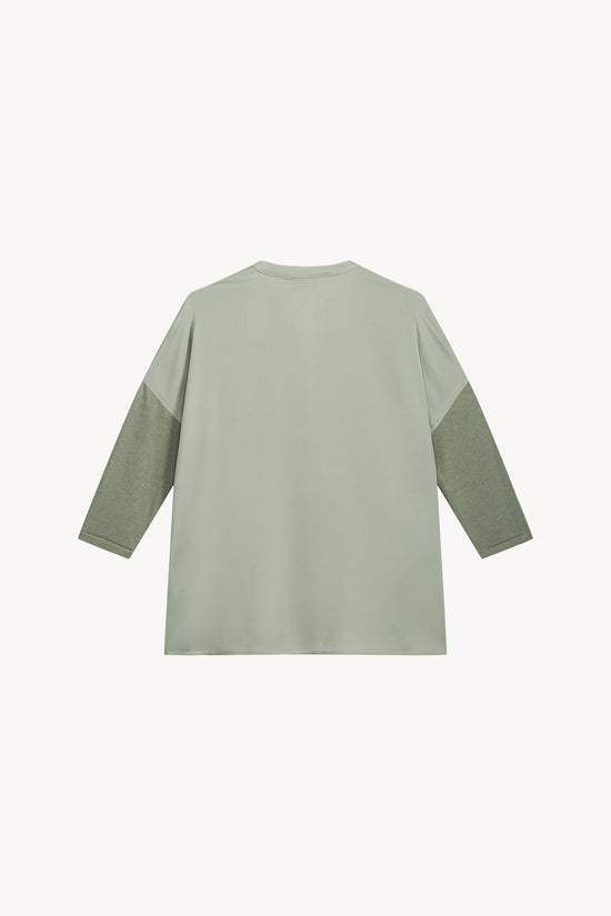 Ce modèle bi-matière sauge, avec son col en V et ses manches en jersey, allie élégance et raffinement.