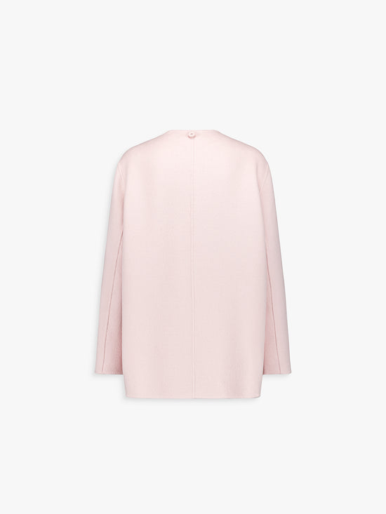 Dos du manteau rose pâle, ligne fluide et épurée.