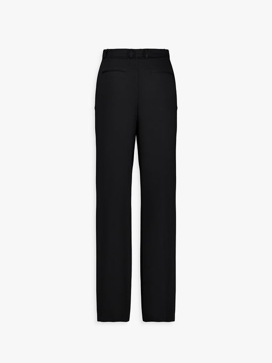 Dos du pantalon noir, poches passepoilées et plis marqués.