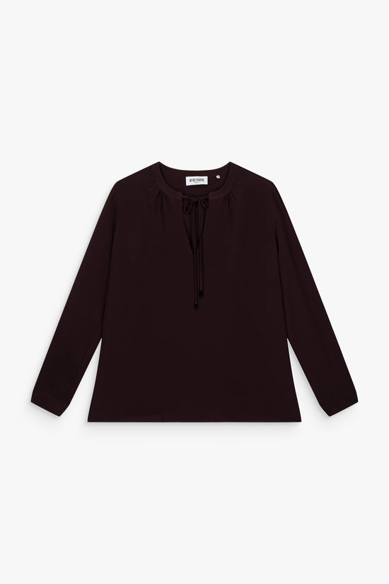 Blouse grenat en soie, coupe ample et manches longues fluides.