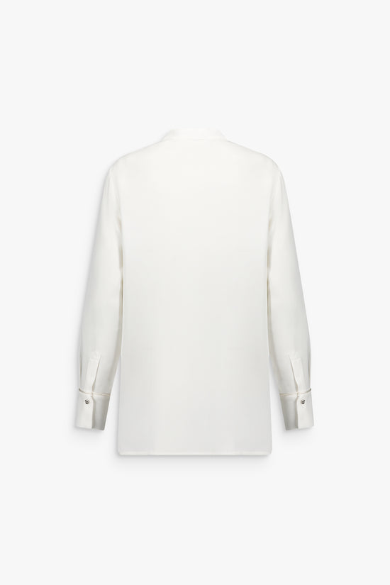 Chemise blanche cassée en soie, plastron structuré, silhouette droite et matière légère.
