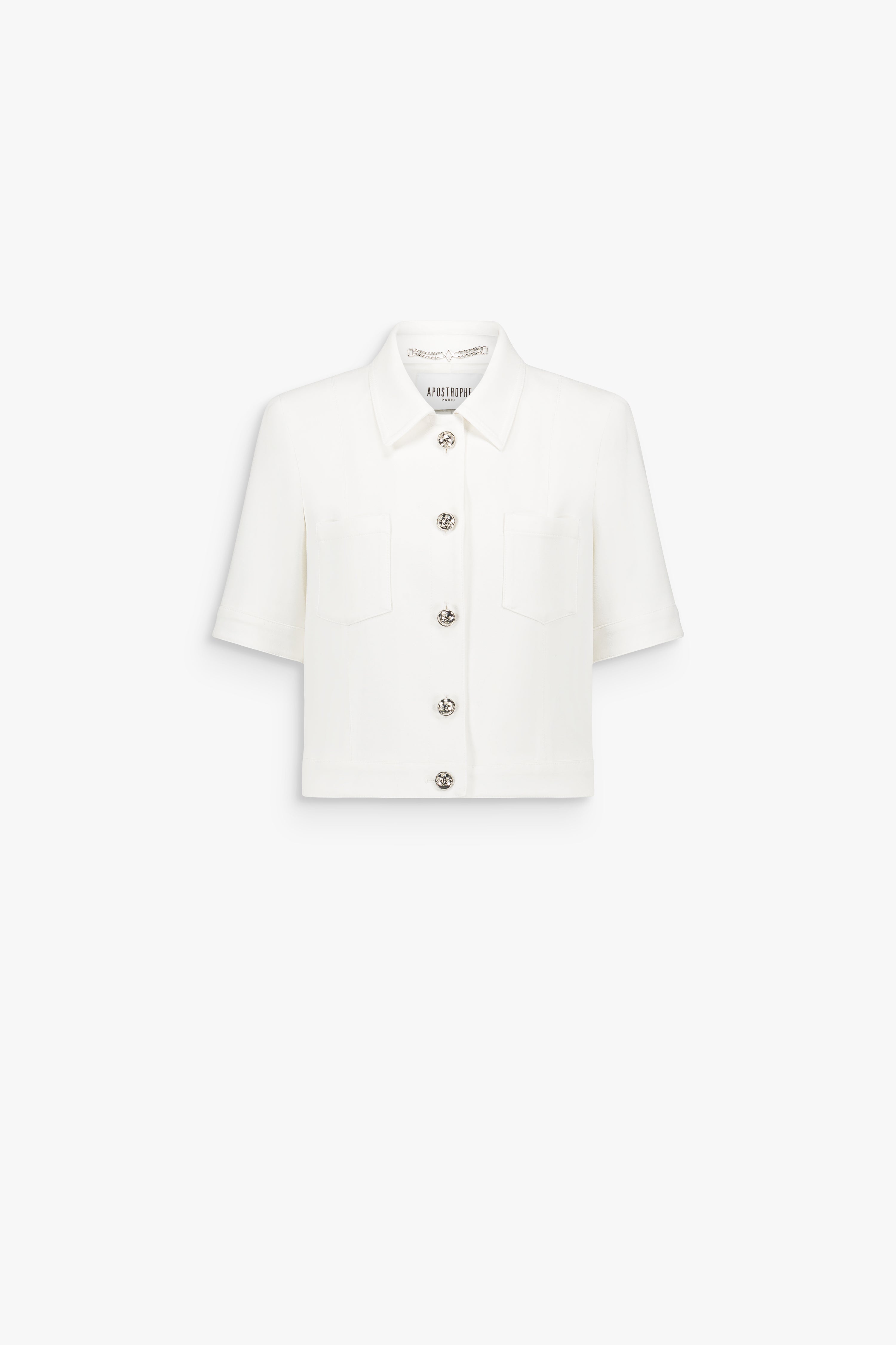Veste courte blanc cassé à col rond, ornée de boutons métalliques et de lignes verticales discrètes.