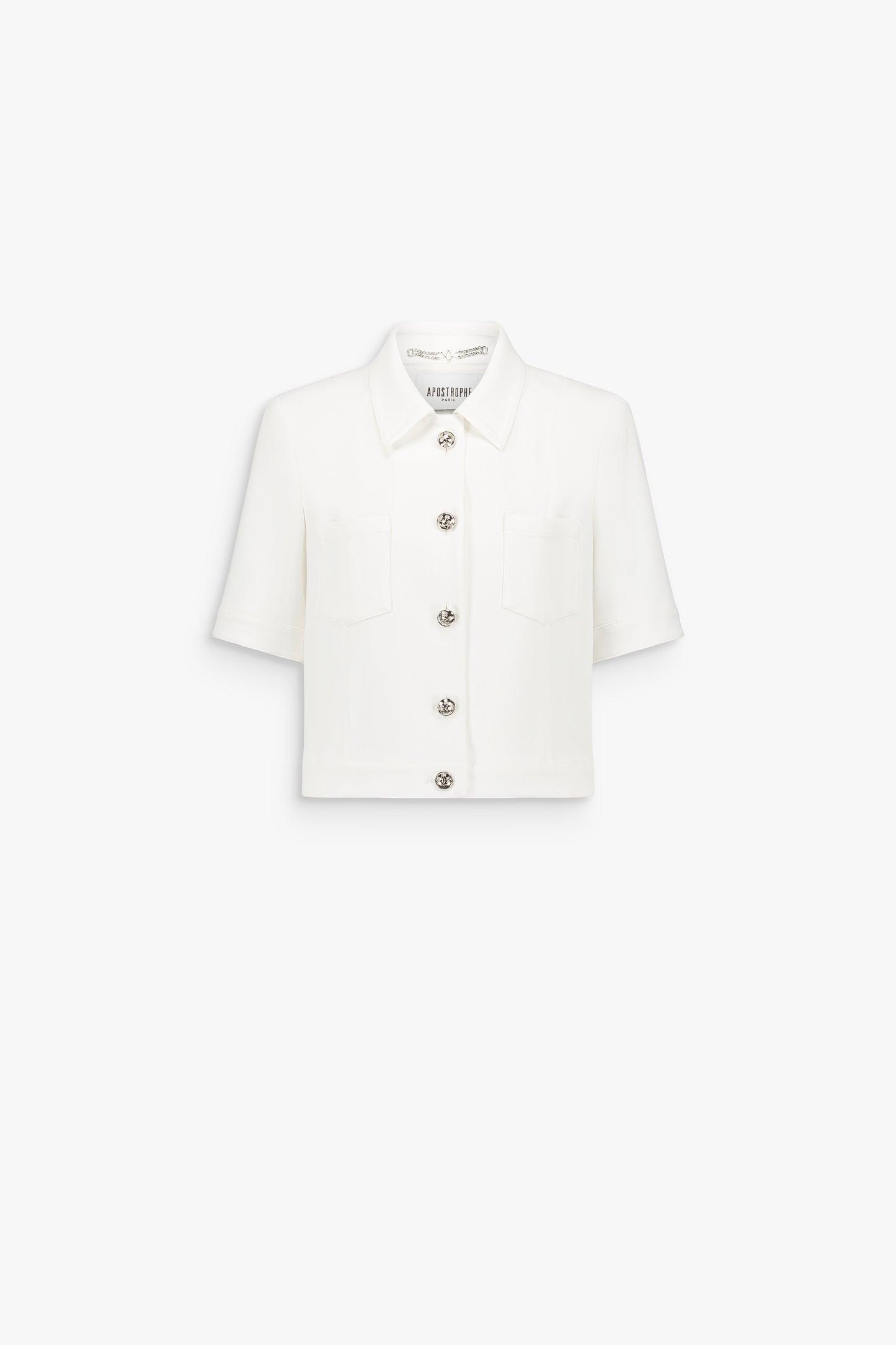 Veste courte blanc cassé à col rond, ornée de boutons métalliques et de lignes verticales discrètes.
