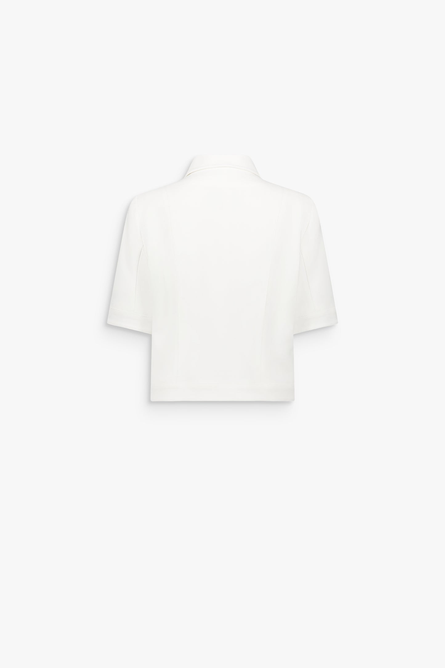 Détail d’une veste blanc cassé structurée avec poches passepoilées et finition épurée.