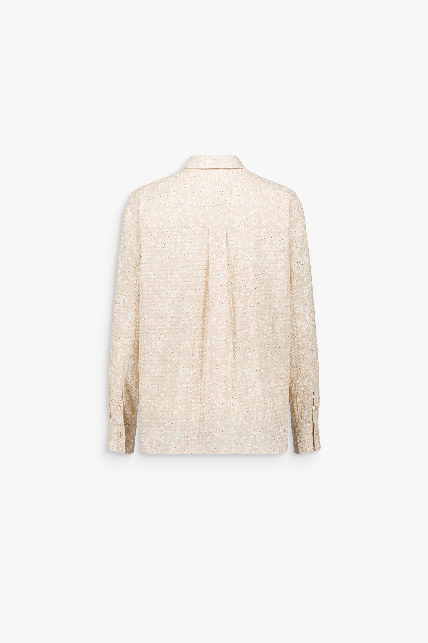 Détail d’une chemise aux reliefs floraux discrets, révélant un jeu de texture lumineux
