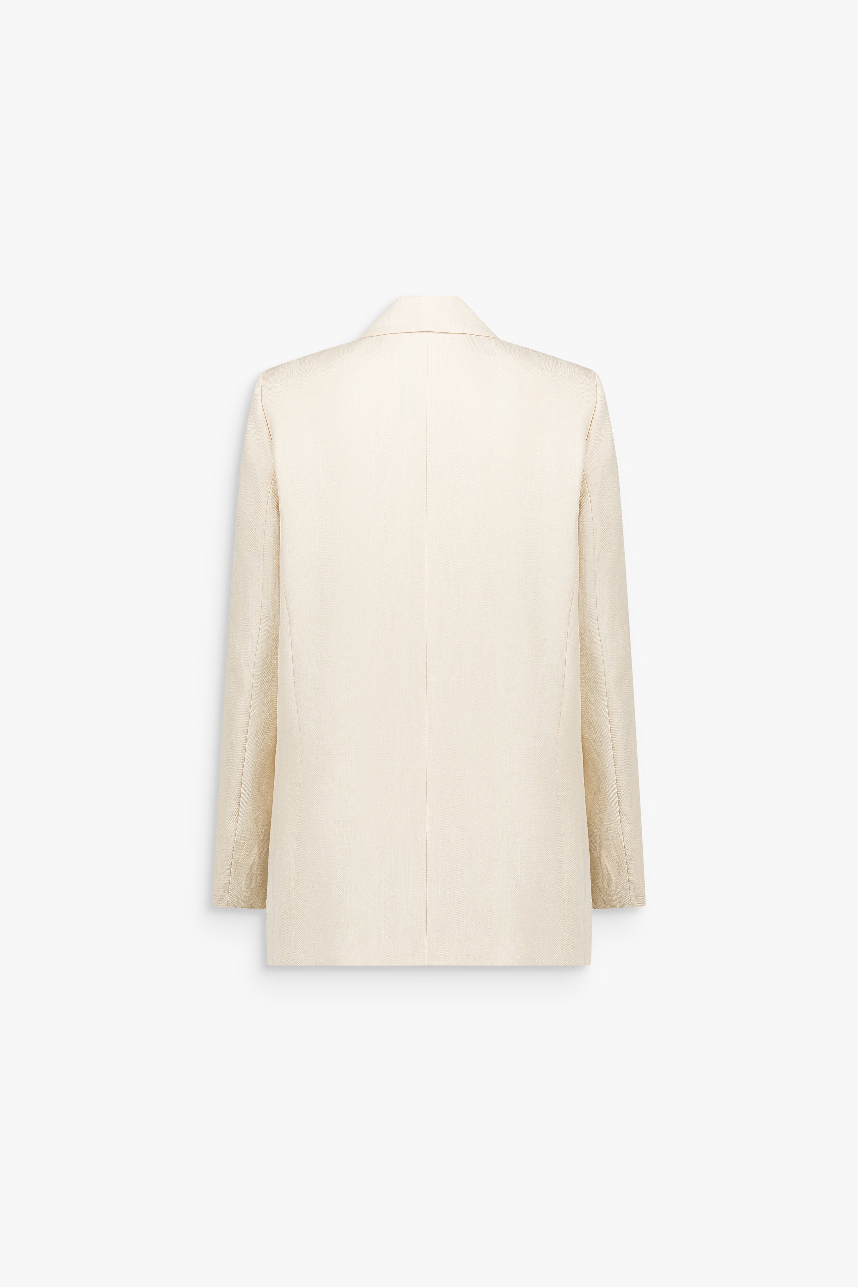 Détail d’une veste tailleur jaune clair, révélant le grain subtil d’un lin mélangé estival.