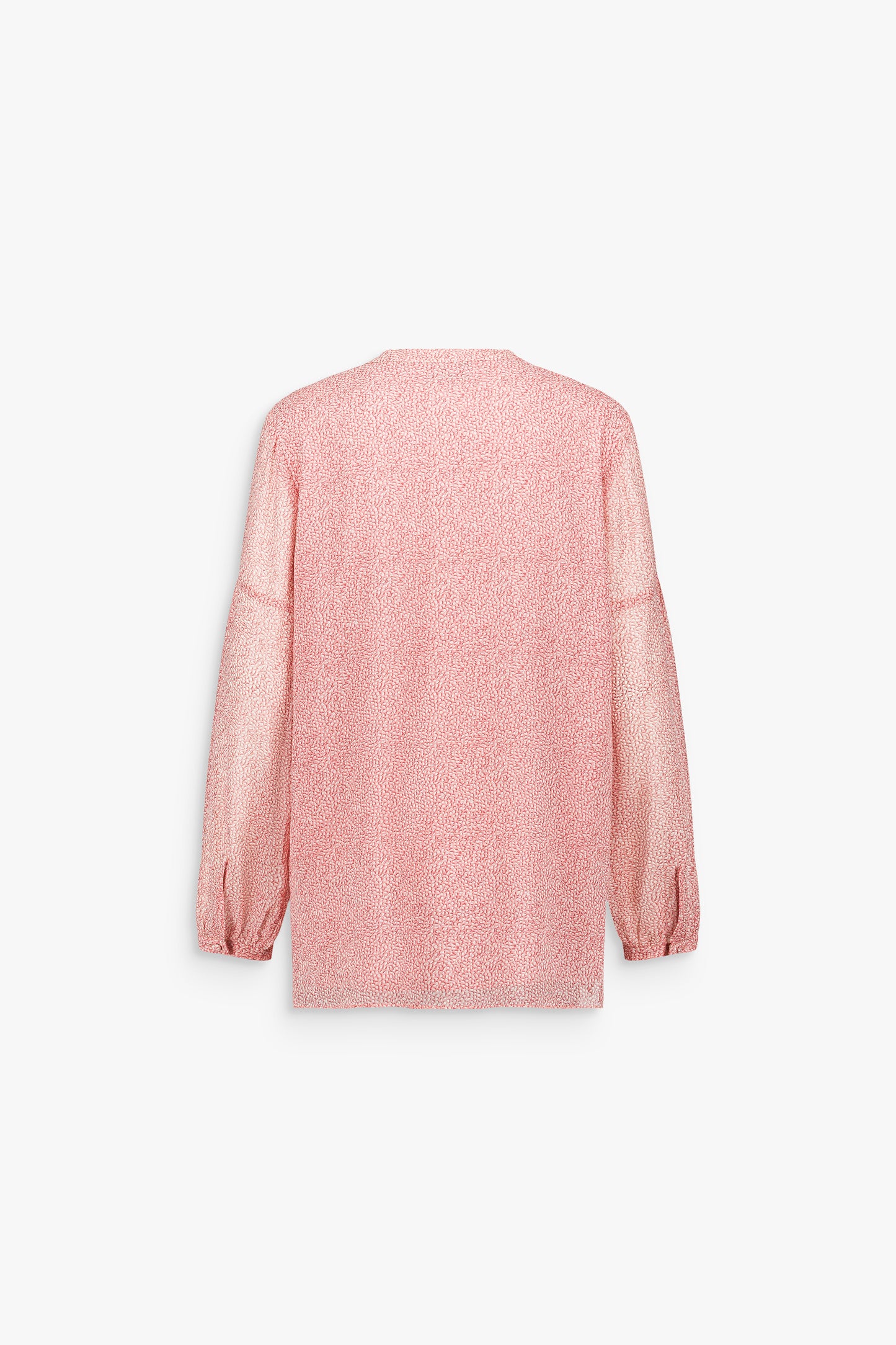 Détail d’une blouse rose pâle au volume maîtrisé, soulignée par des manches ballon élégantes.