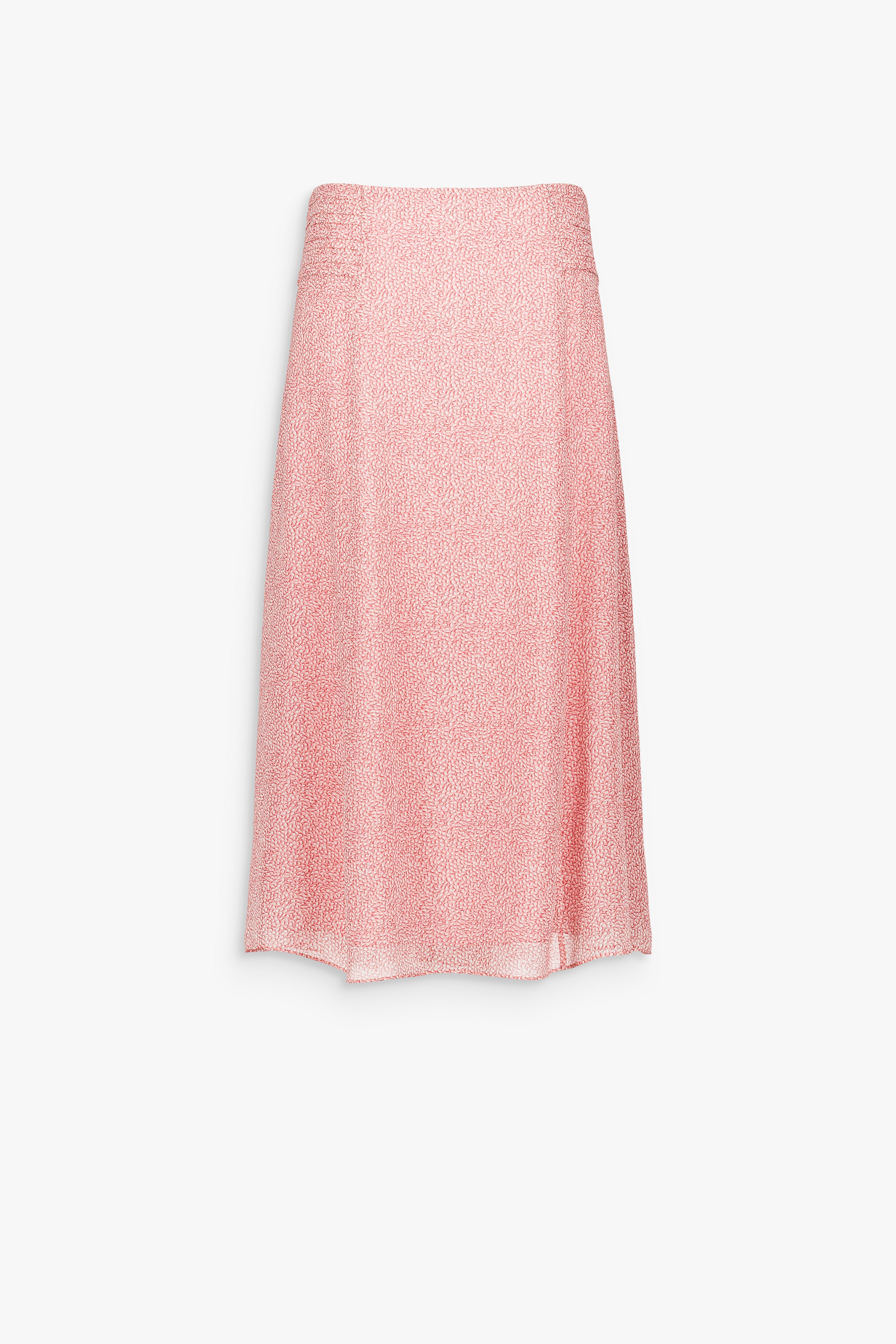 Jupe longue en soie rose pâle à imprimé délicat et tombé fluide.