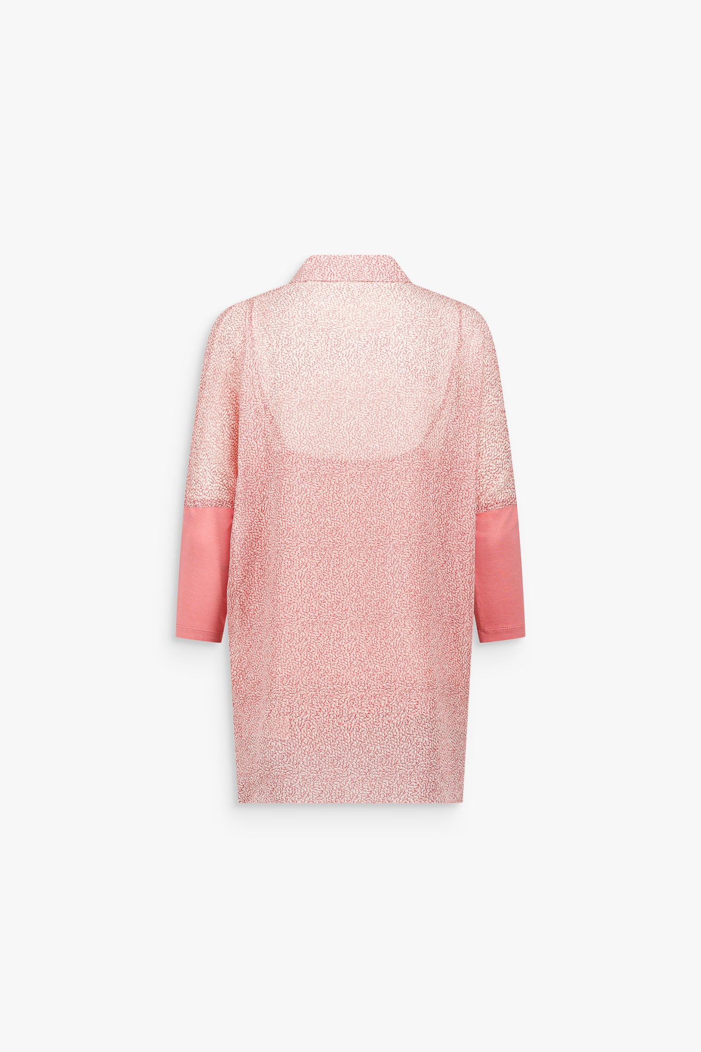 Détail d’une tunique en soie rose pâle à coupe ample, révélant un motif subtil et une allure fluide.