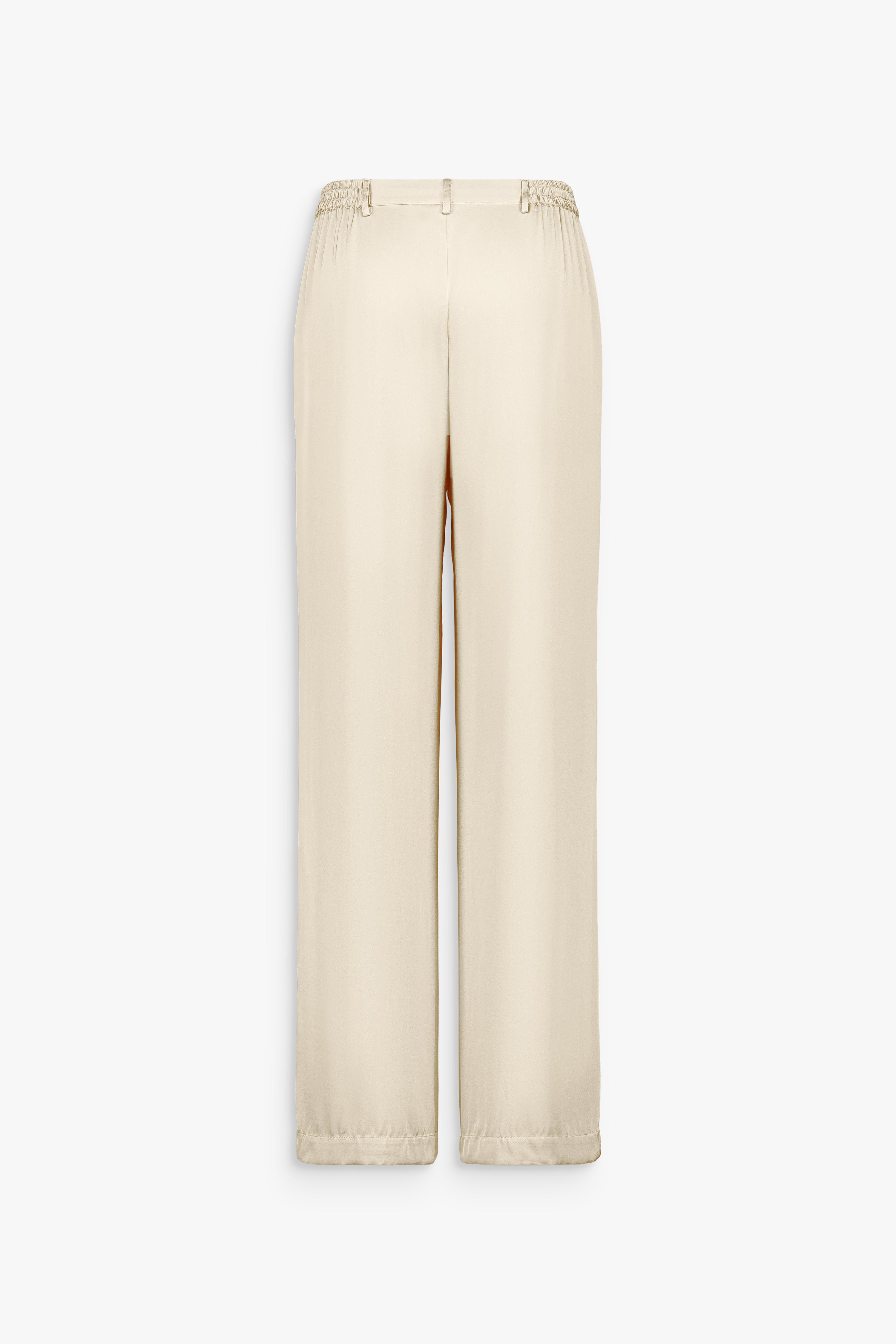 Fronces discrètes devant et dos structurant la taille du pantalon en soie jaune clair.