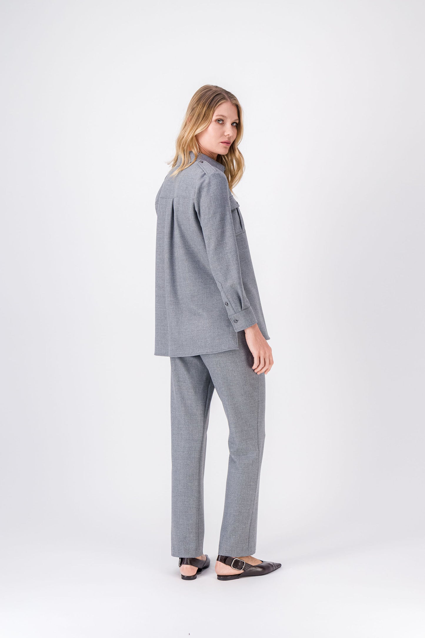 Détail des pattes d’épaule et des boutons argentés sur la chemise gris moyen.