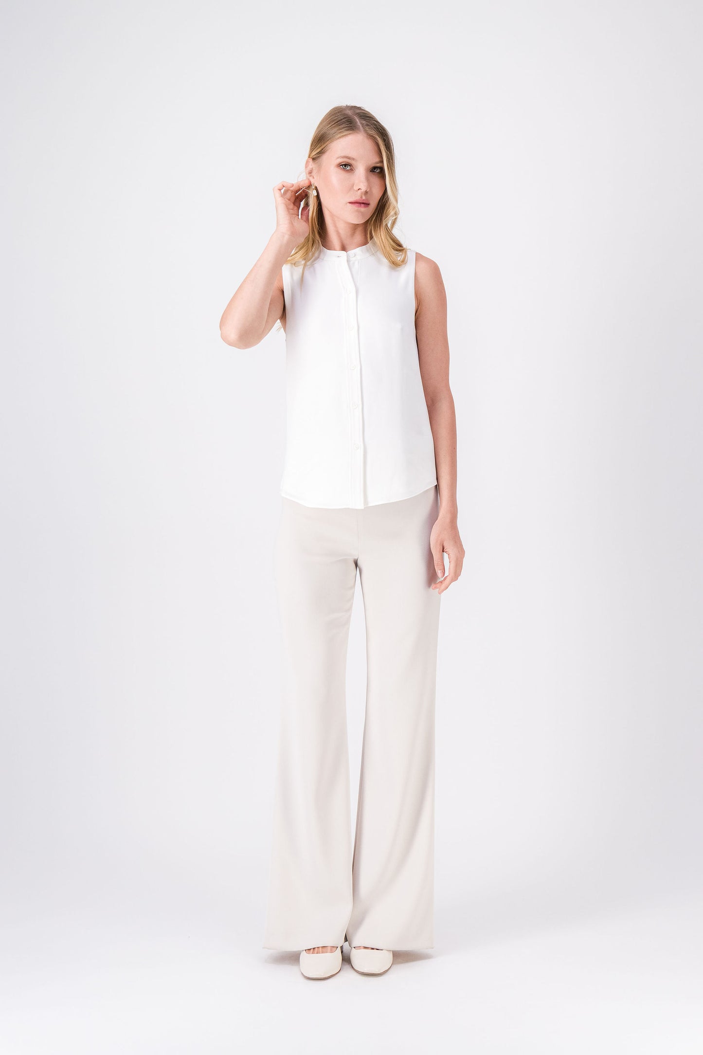 Blouse sans manches en soie blanc cassé, col mao et patte de boutonnage raffinée.