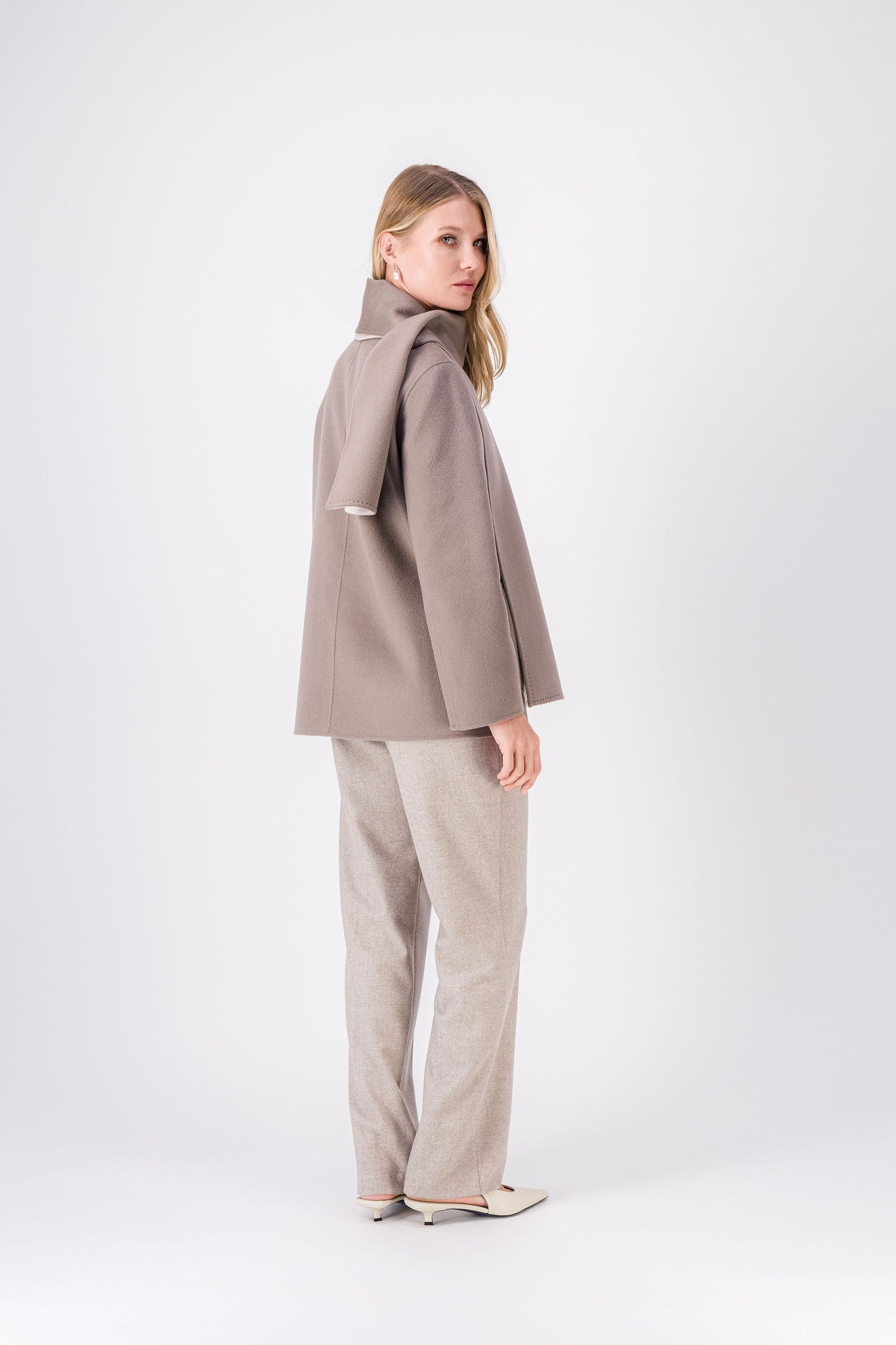 Détail des poches plaquées et de l’écharpe intégrée sur le manteau réversible.
