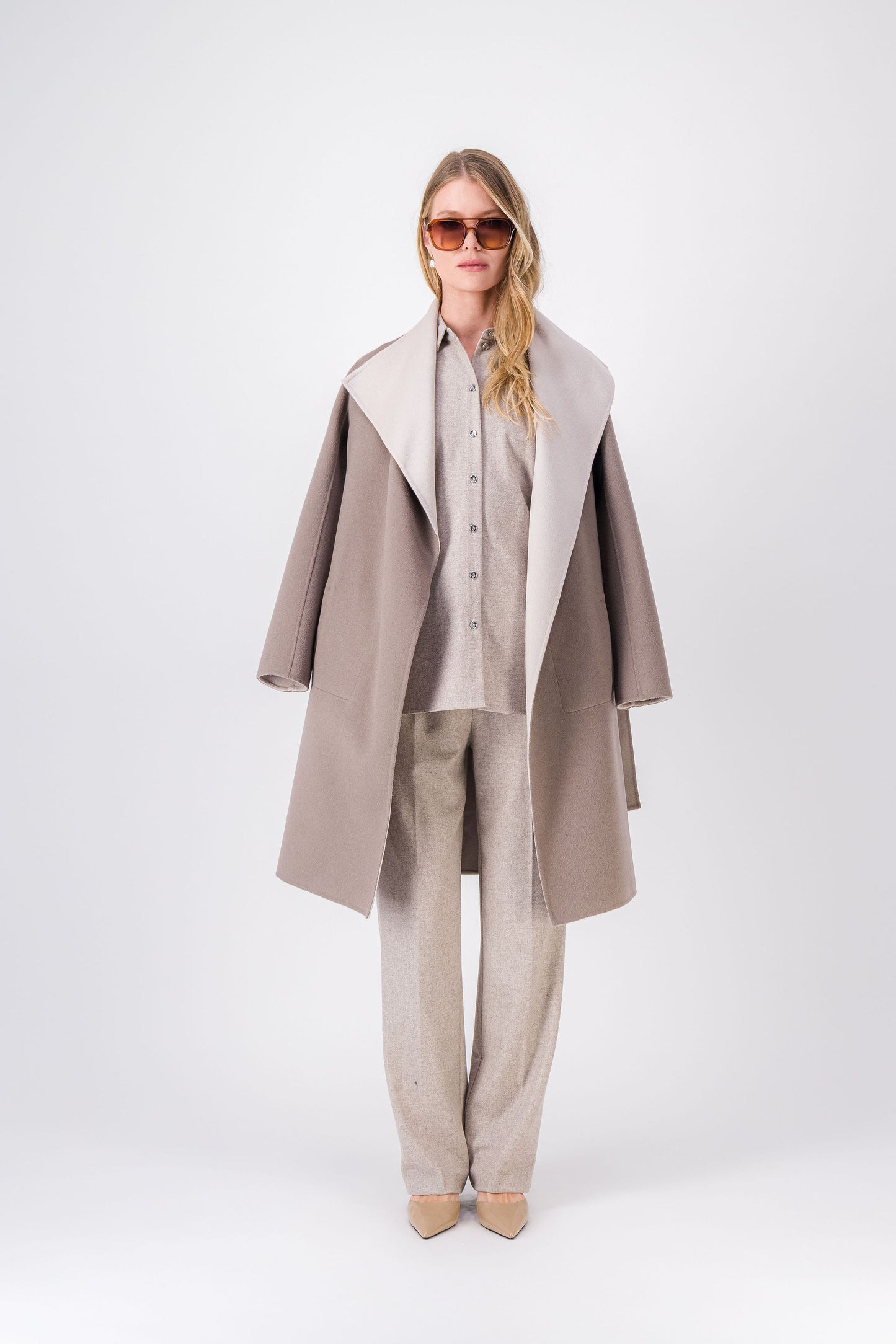 Manteau long taupe moyen en laine et cachemire, coupe ample avec ceinture pour souligner la taille.