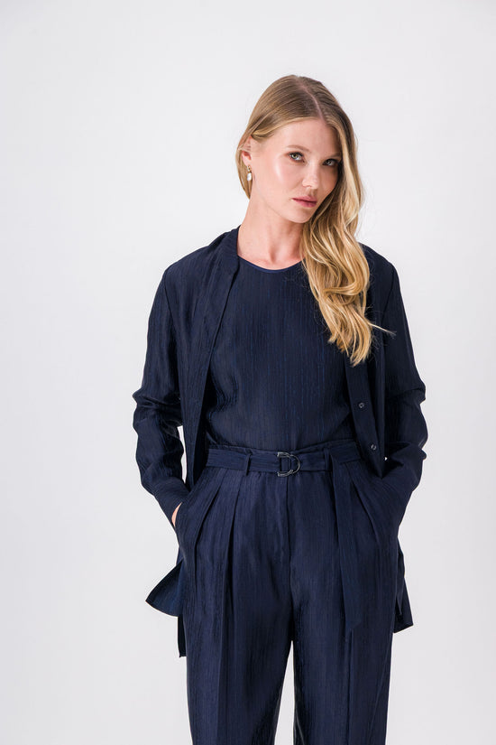 Pantalon marine à taille ceinturée, coupe droite fluide avec plis subtils et boucle raffinée.