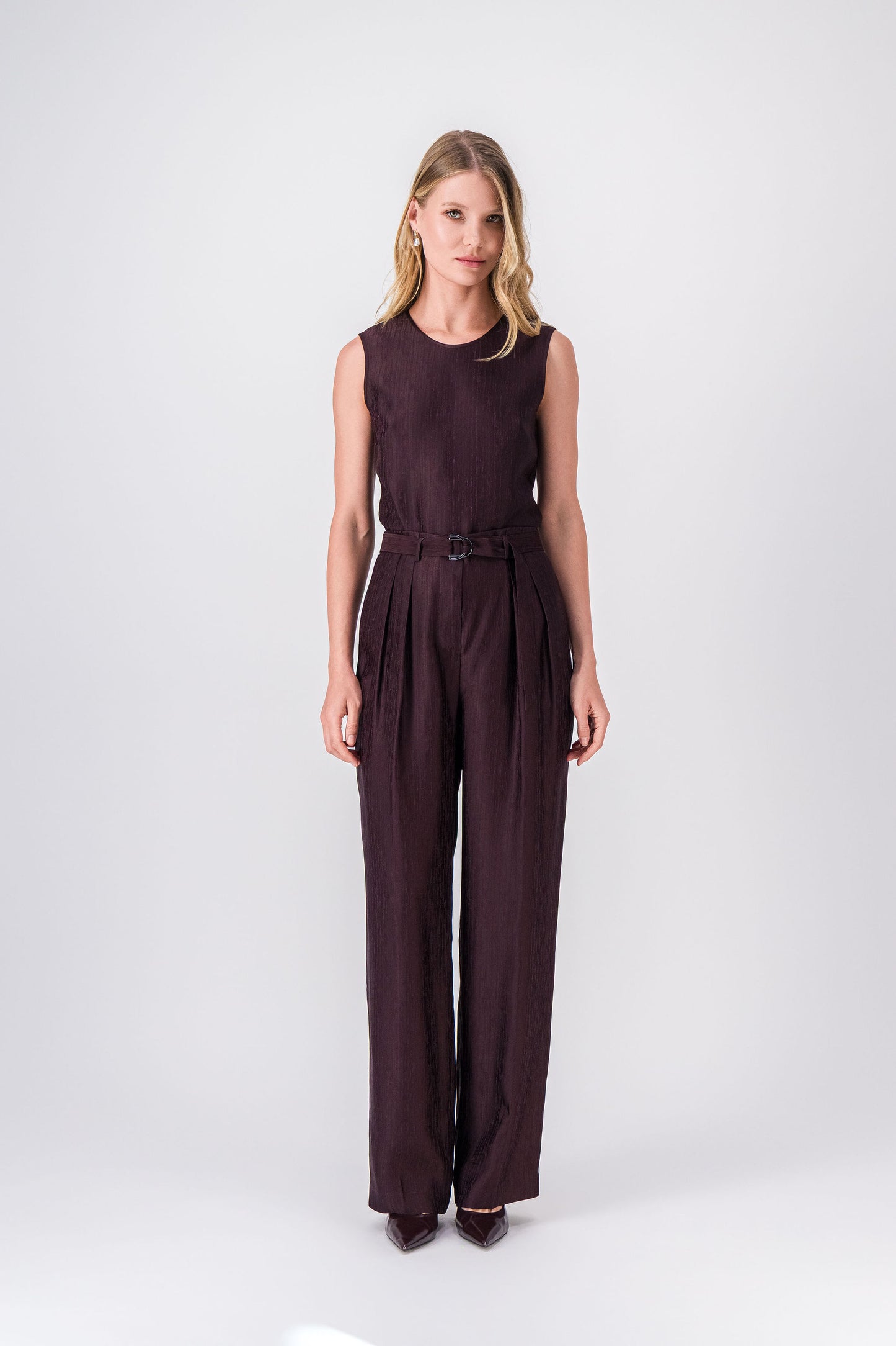 Pantalon grenat à coupe droite, ceinture à boucle en métal et plis avant subtils.