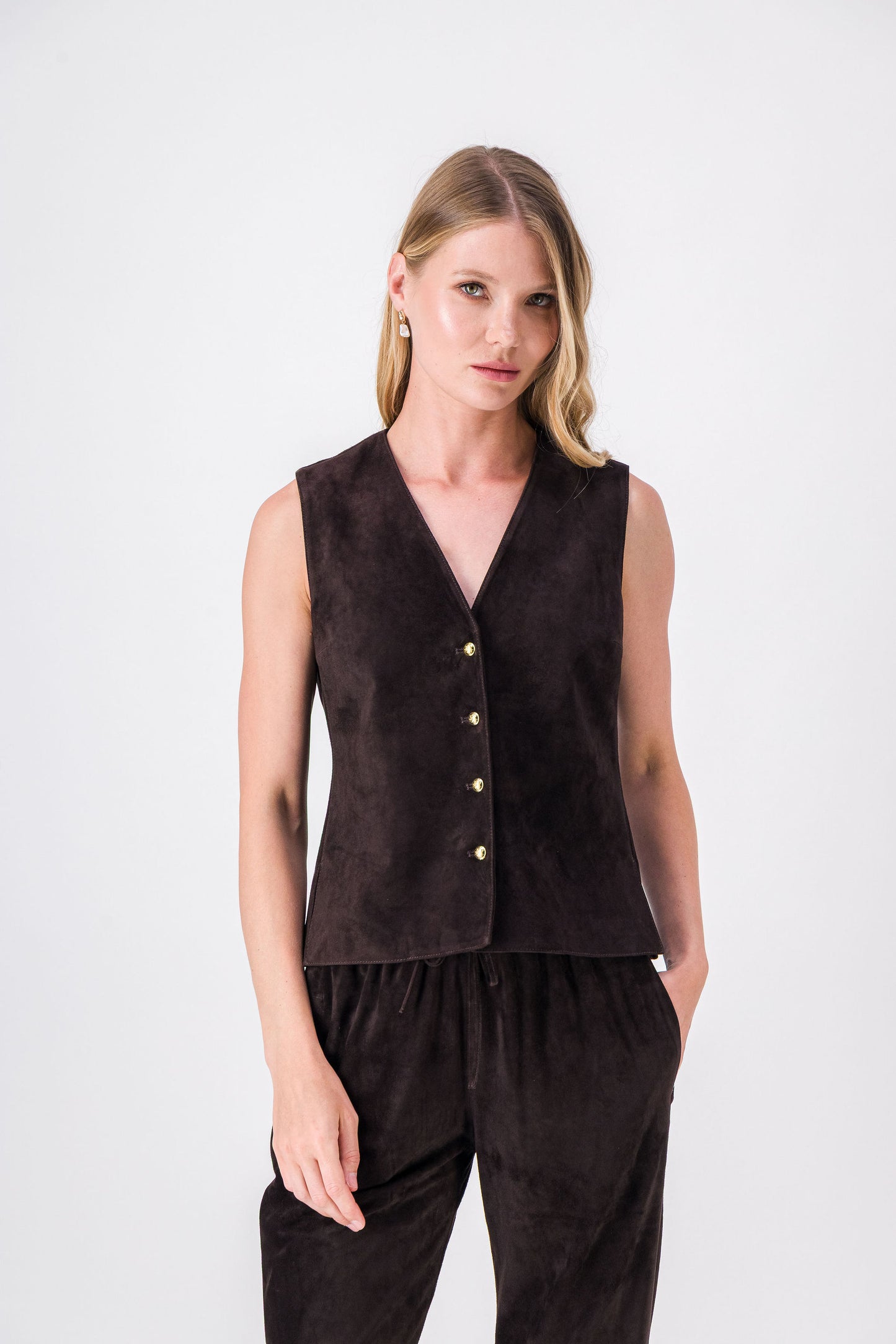 Gilet en daim ébène ajusté, orné de boutons dorés et surpiqûres raffinées, à porter seul ou en superposition.