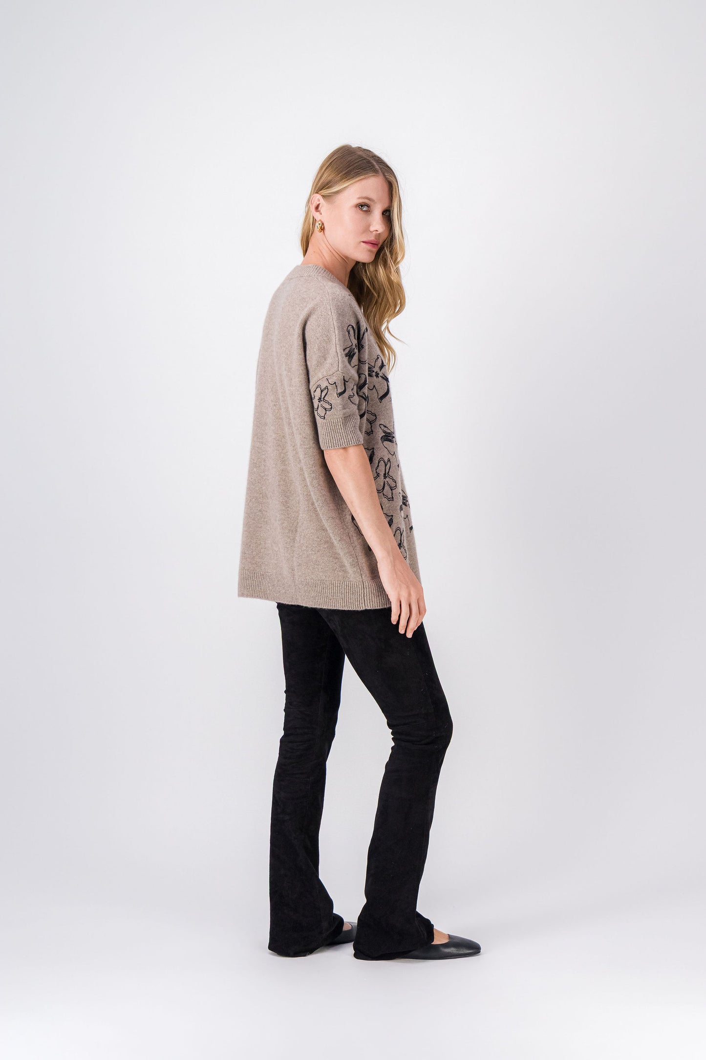 Vue du pull taupe en cachemire, silhouette ample et détails floraux délicats.