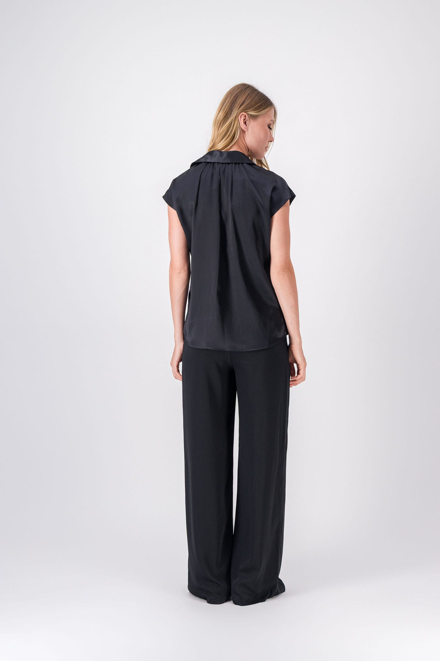 Détail du col chemise et des boutons sur la tunique noire en soie.