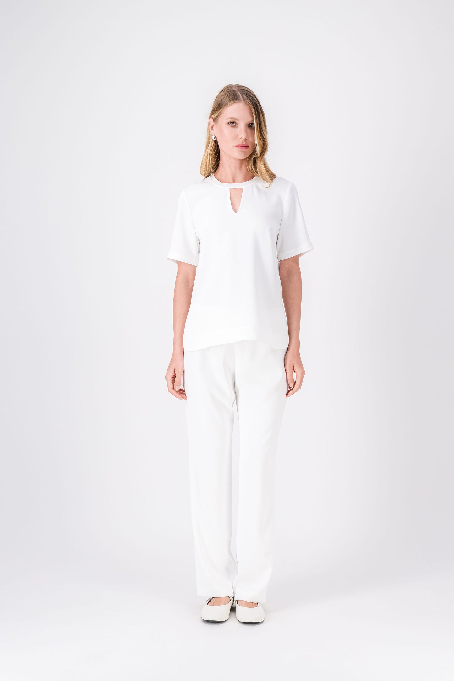 Top blanc cassé à manches courtes, coupe droite avec fentes latérales et col décoré.