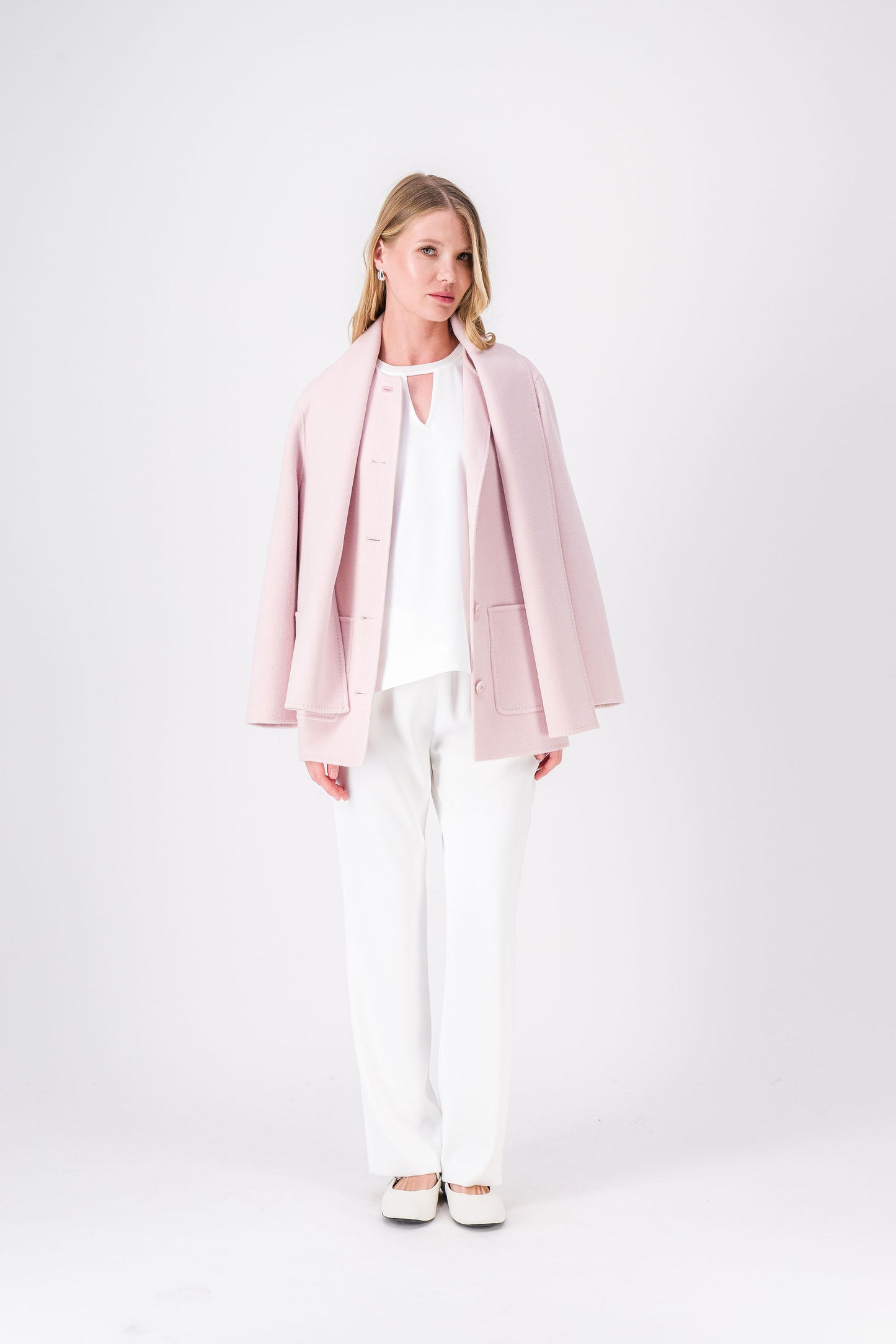 Manteau mi-long rose pâle en laine et cachemire, coupe droite avec poches plaquées et écharpe intégrée.