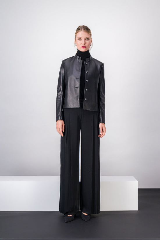 Veste en cuir noire, coupe droite avec manches longues et boutons blasons raffinés.
