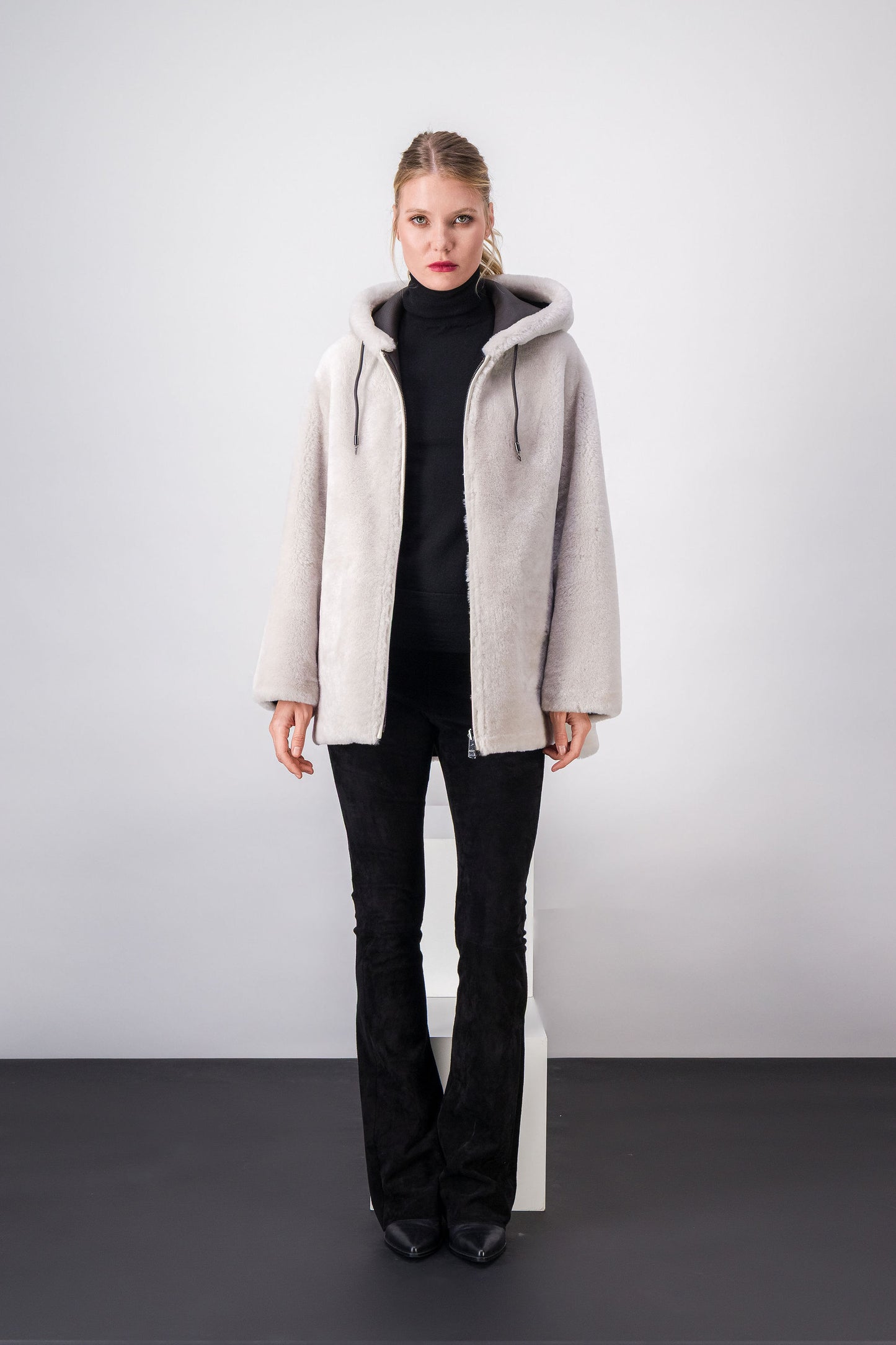 Manteau court en fourrure, coupe droite classique avec fermeture éclair et cordons de serrage discrets.