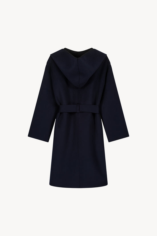 Coupe ample avec capuche. Manteau réversible bi-couleur, col tailleur, ceinture coordonnée. Détails couture main en point feston. Poches plaquées fonctionnelles.