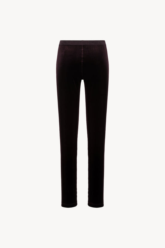 Coupe ajustée en velours grenat. Taille élastique, zip latéral discret.